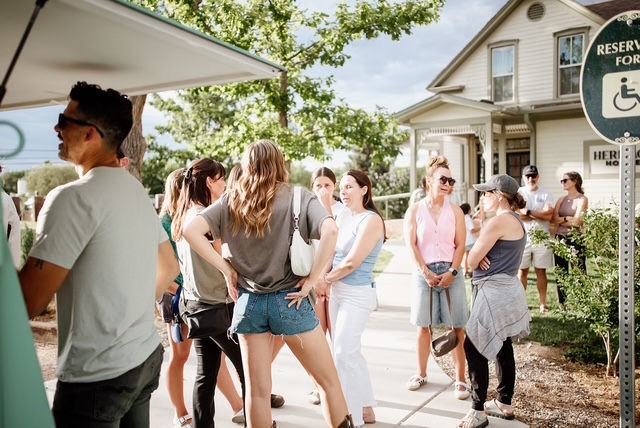 A crowd mingling beside the trailer at a summer event