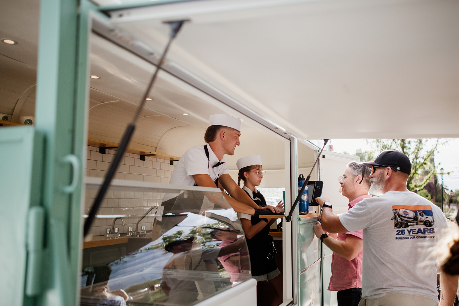 Two servers taking a guest's order at the trailer window