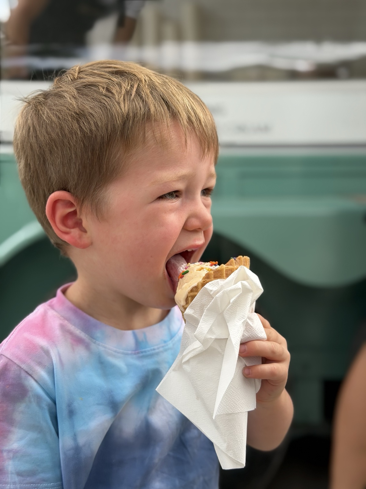 A child taking a big bite of an ice cream waffle
