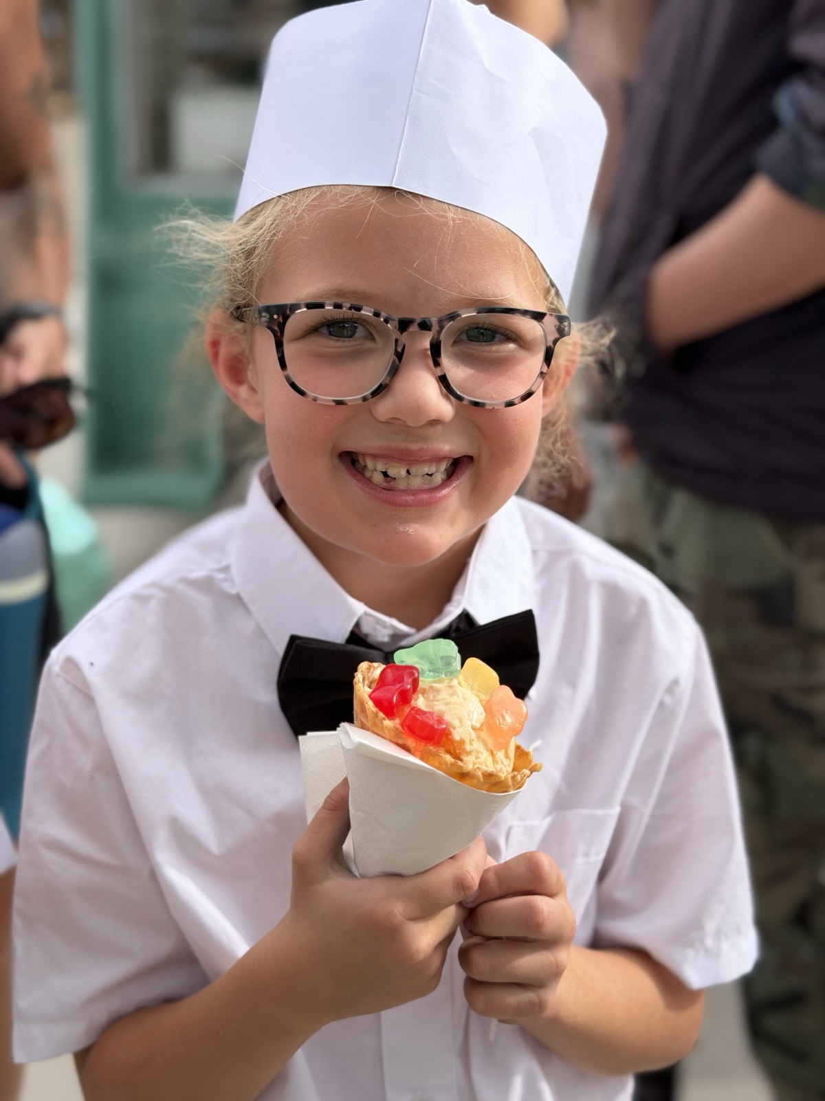 A young server holding a waffle cone topped with candy