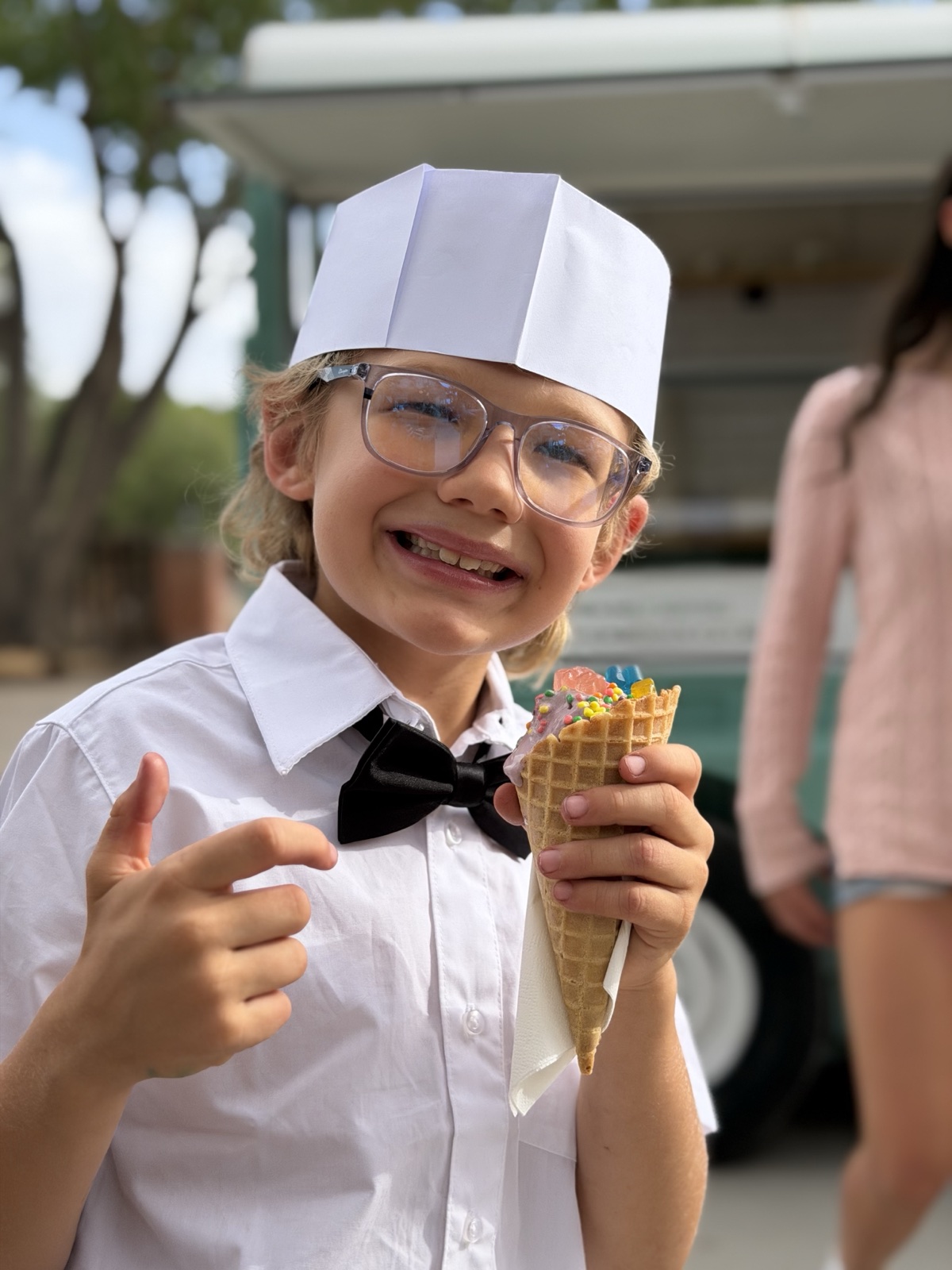 A young server giving a thumbs up with a waffle cone