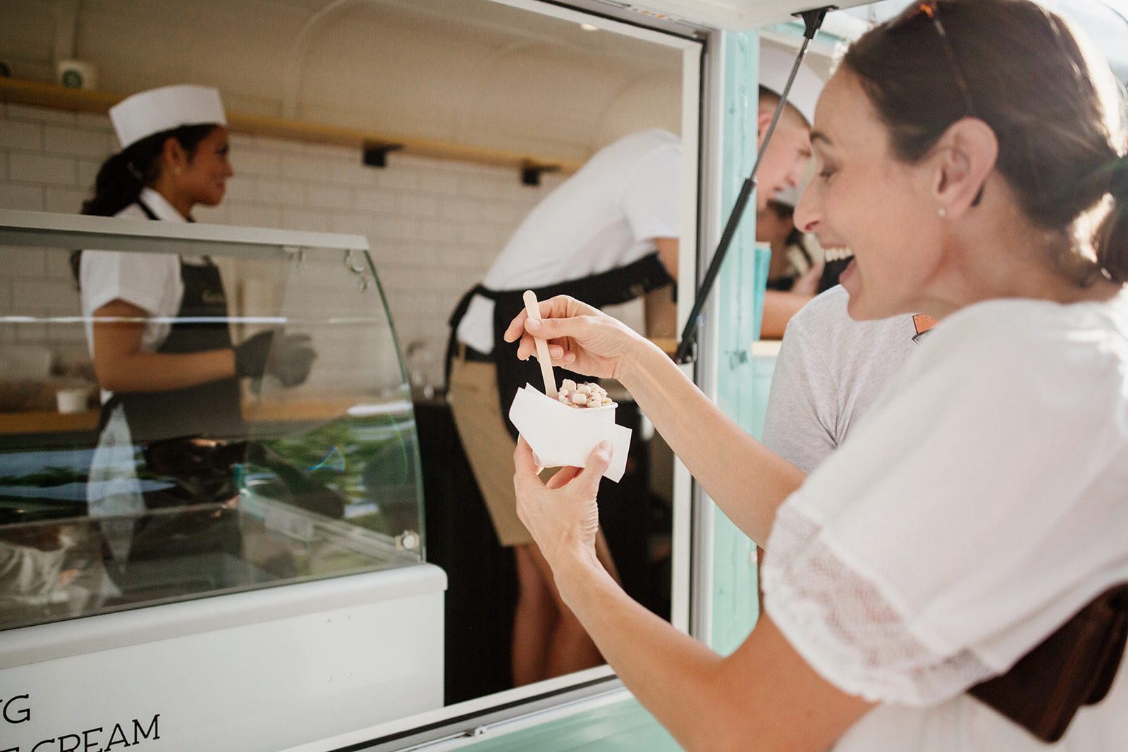 A guest laughing as she is handed a fresh scoop at the trailer window